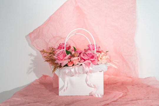 Pink bouquet with roses in a white box on a pink background