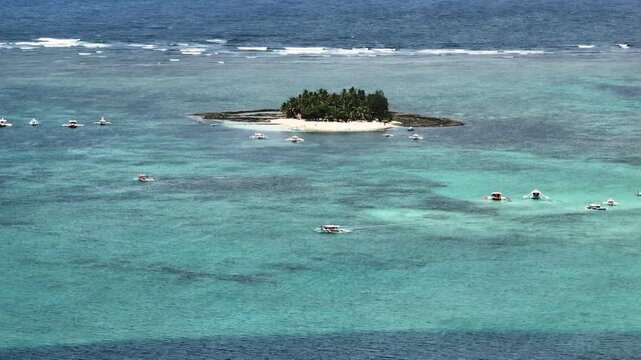 Palm covered island with white sand beach and clear blue water. Guyam Island. Siargao, Philippines.