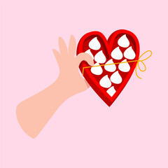 Hand holding a heart-shaped box of sweet treats
