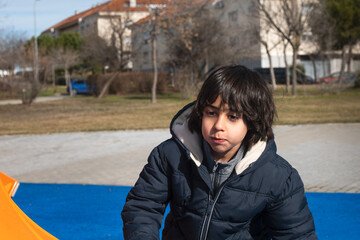 Fototapeta premium Young boy playing outdoors at urban playground on sunny day