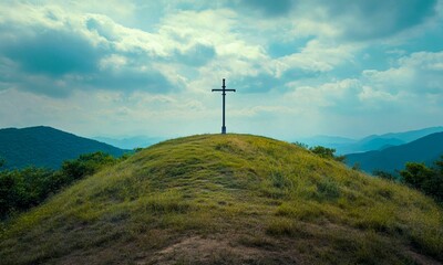 Obraz premium Christian Cross on a Grassy Mountain Peak with a Blue Cloudy Sky and Scenic Vista