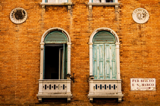 detail of windows with open green shutters on a historic house in Venice - one window is closed and the other is open