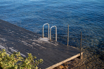 Swimming pool ladder leading into the sea from wooden platform