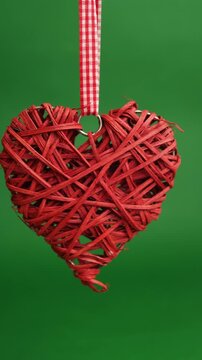 Red Woven Heart Ornament Hanging From Gingham Ribbon Against Green Backdrop, Handmade Rustic Valentine