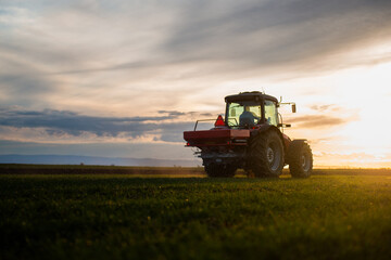 Fototapeta premium Tractor spreading artificial fertilizers in field