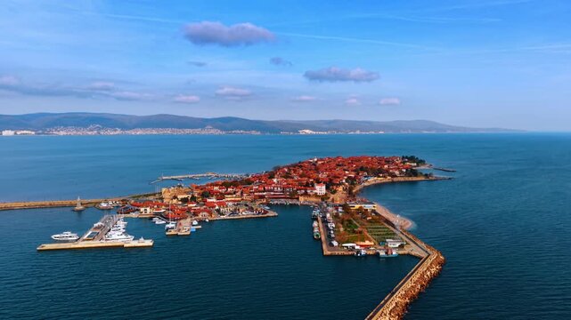Aerial view of ancient town on a peninsula with harbor. High angle perspective of a historic town with red roofs located on a peninsula with a harbor and boats.