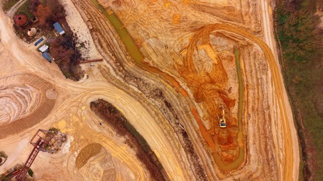 High angle view of sand quarry layout with machinery. Aerial perspective of sand extraction site featuring conveyors, excavator, and water channels.