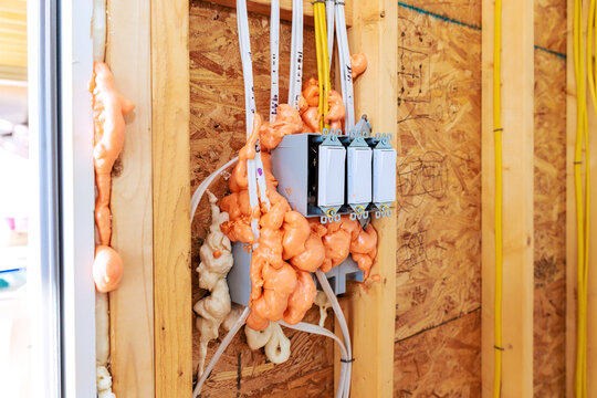Electrical work in house with fire proof foam insulation covering wires switches on wooden wall