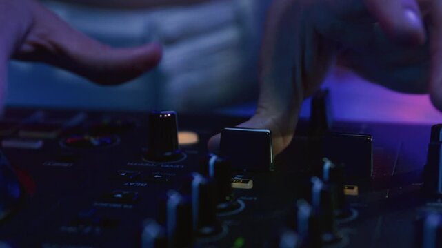 Close-up: DJ man hands playing set in night club, controling sound console. Playing music at party festival. Finger of male disc jockey touching twister button or slider.