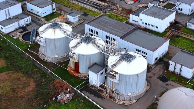 Close up of three large anaerobic digester tanks. High angle shot of metal cylindrical tanks for biogas production or sludge treatment.