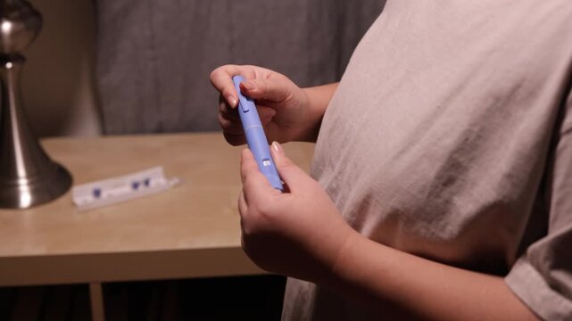 A horizontal close up of an young woman opening a needle on pre-filled pen injector to prepare it for taking medicine
A young woman opening a needle on pre-filled pen injector with semaglutide