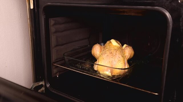 Une personne mettant un poulet r&ocirc;ti au four.