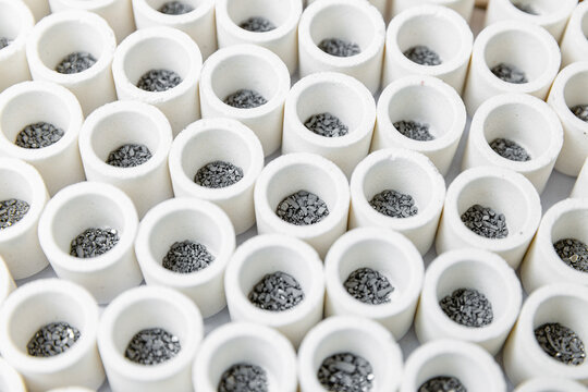 Close up of ceramic crucibles with metal granules in rows