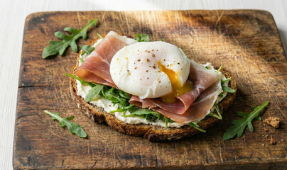 Gourmet open faced sandwich with poached egg and ham on rustic bread