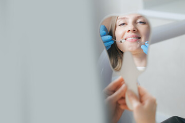 Young caucasian female smiling during dental examination with mirror reflection, caries treatment