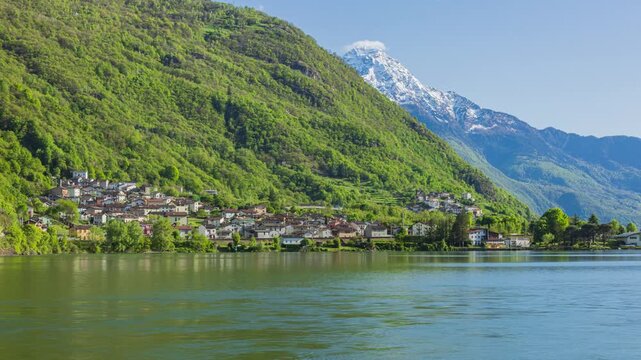 Time lapse, panoramic view on a lake with mountains. Small Italian municipality near lake. Verceia, Lake Mezzola, Lombardy, Italy.