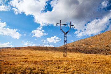 High-voltage pylons in the mountains against the blue sky