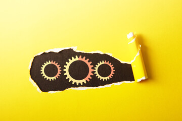 Paper with gears and torn edges on yellow background, space for text
