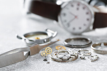Mechanism of vintage wrist watch, gears and tool on grey table, closeup
