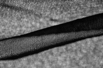 Abstract black mesh fabric texture with soft bokeh background. © Trygve