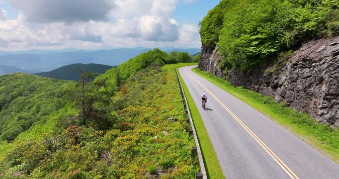 Cyclist riding a road bike along a scenic route in Appalachian Mountains, blending athletic performance, travel inspiration and outdoor exploration.