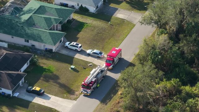 Fire truck and ambulance parked curbside while paramedics enter home during medical incident.