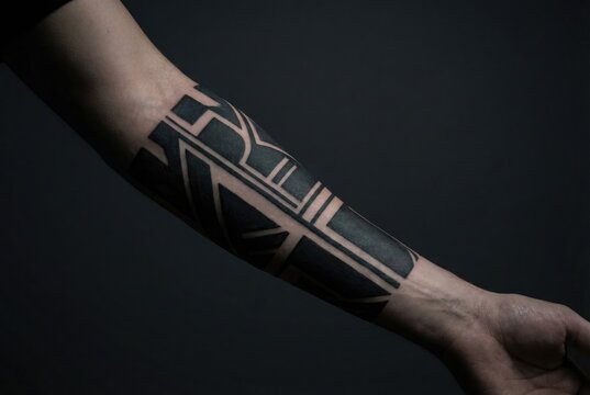 A close-up of a bold blackwork geometric tattoo on a person's forearm against a dark background.