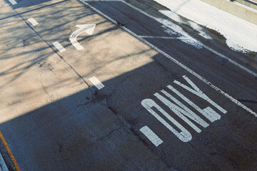 Fototapeta premium Road with a turn arrow and painted direction only sign under a clear sky in a city area during daylight hours