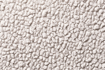 Beige boucle fabric texture closeup. Soft upholstery material surface detail. Curly textile background with looped fibers. Neutral interior design pattern. Warm cozy cloth structure macro view. © Paweł Michałowski