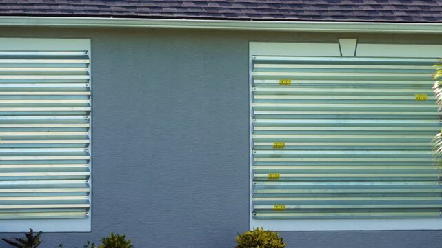 Steel storm shutters for hurricane protection of house windows. Protective measures before natural disaster in Florida