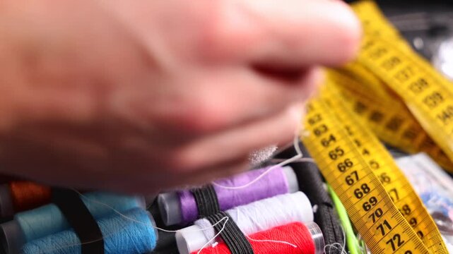 Gros plan sur une personne en train de recoudre une chaussette avec un trou avec du fil et une aiguille.