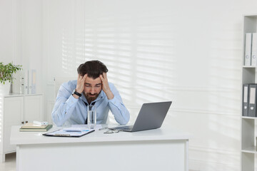 Fototapeta premium Man suffering from heat at table near white wall indoors, space for text