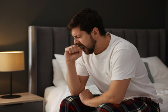 Unhappy man feeling fatigue on bed at home, space for text