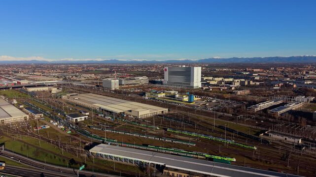 Aerial view of train depot and cityscape with alps in the background