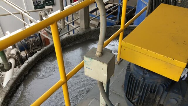 Thick gray pulp bubbling and churning inside a large industrial processing tank at a mineral plant