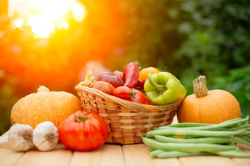 Harvest. A basket of fresh vegetables tomatoes, peppers, garlic, and green beans  rests on a wooden...