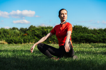 Fototapeta premium Woman practicing yoga on grass in bright sunlight