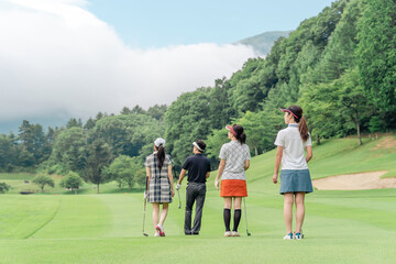 Obraz premium Male and female golfers walking on the golf course