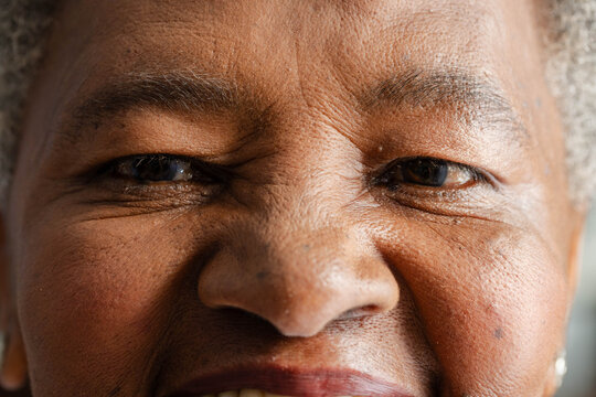 Senior African American woman smiling and squinting in studio, small stud earring showing