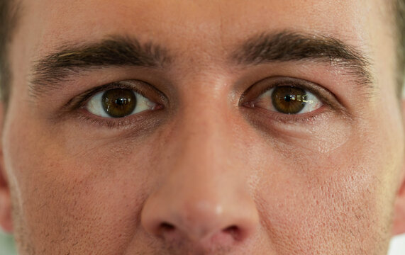 Adult male face filling frame, focusing eyes and nose, showing skin pores and stubble in studio
