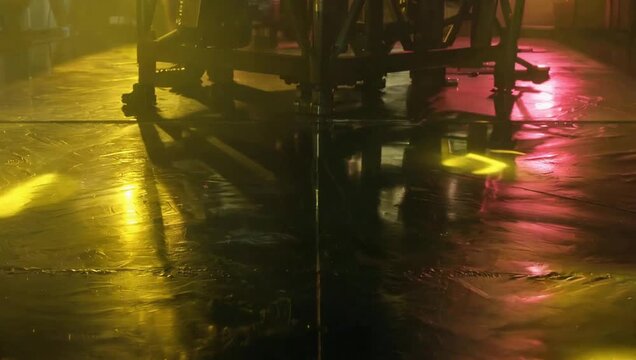 Colorful light reflections on a wet floor at night.