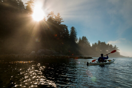 Canada, BC, Vancouver Island.  Kayaker explores the shoreline of Clarke Island in the Broken Island Group, part of the Pacific Rim National Park on the Pacific coast. 