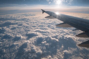 Obraz premium Airplane wing above clouds illuminated by sunlight at high altitude