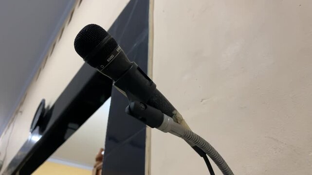 Close perspective of mosque azan microphone attached to wall indoors. Audio device for sermon and prayer guidance creating focused, solemn, and spiritual ambiance.