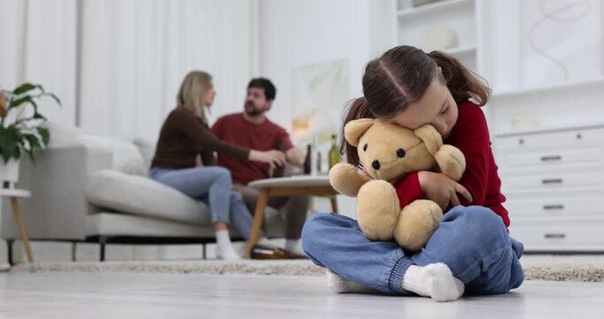 Alcohol addiction. Man and woman drinking beer on sofa at home, focus on their sad daughter with toy bear