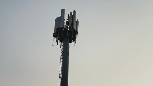 Closeup view of a monopole cell tower with antennas mounted near the top, showing a freestanding telecom structure forming part of a cell site for wireless communication.