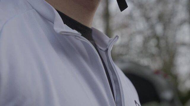 Close up of hand pulling zipper on white cycling jacket outdoor