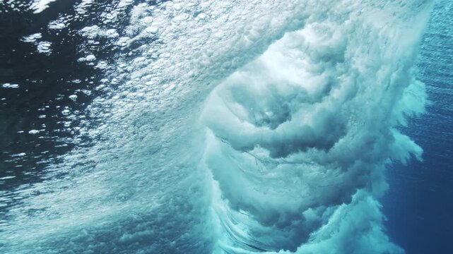 Breaking underwater wave with foamy bubbles and luminous blue ocean texture
