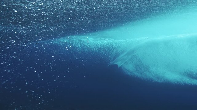 Clean underwater wave line glowing turquoise with suspended bubbles and minimal ocean texture