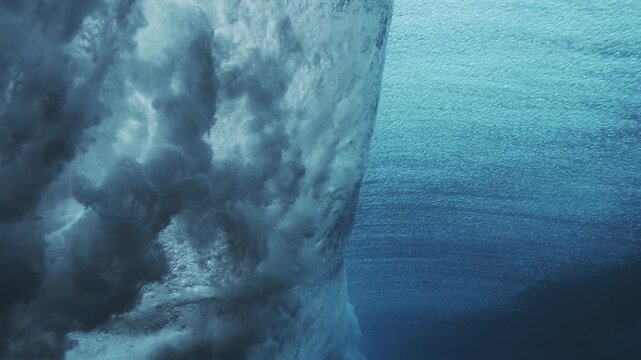 Breaking underwater wave with textured surface and turquoise light near the face